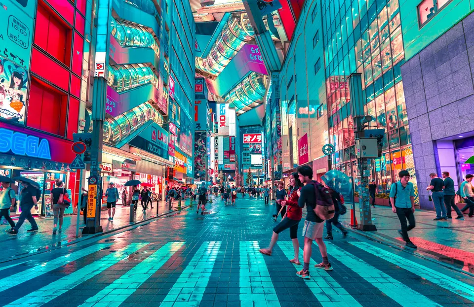 People exploring a colorful Tokyo shopping street illuminated by signs