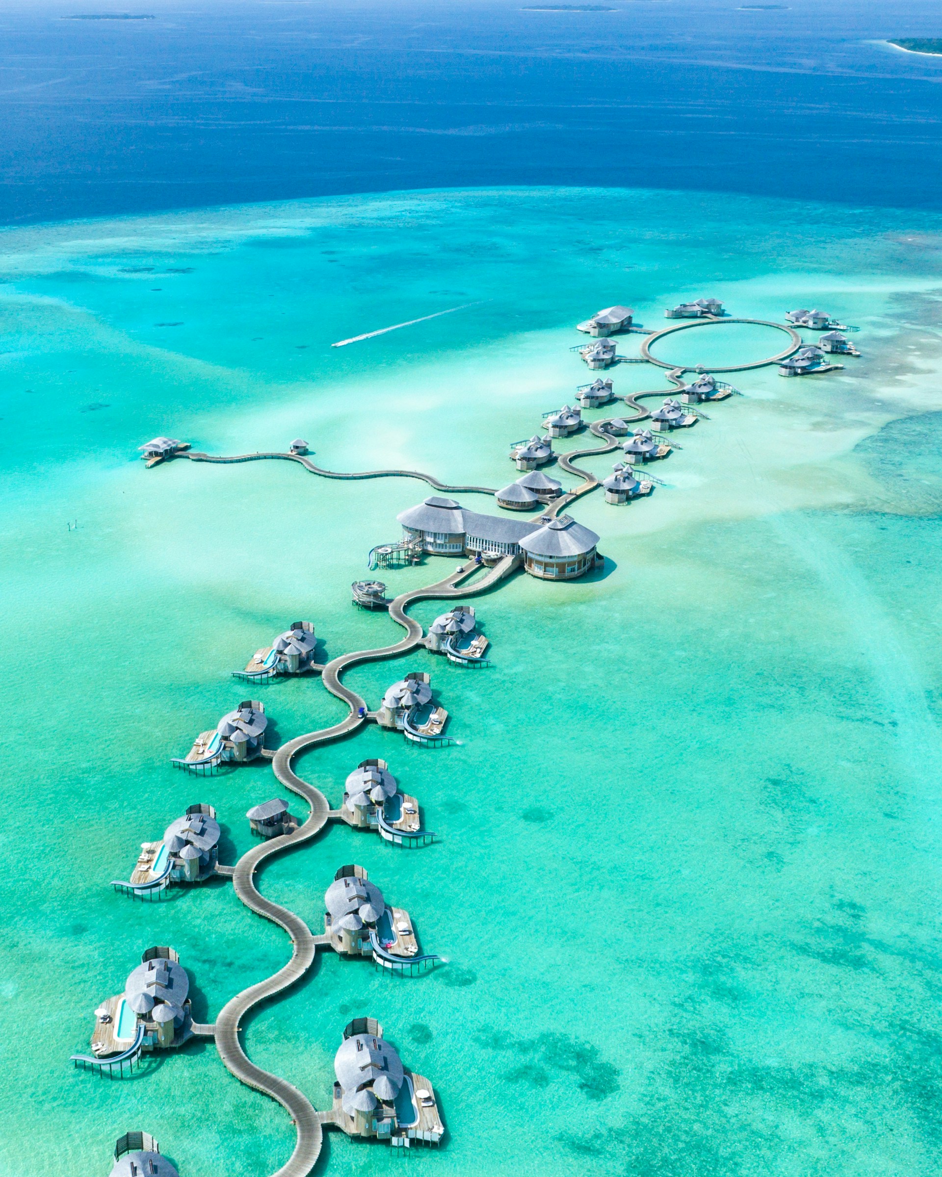 Bright turquoise lagoon and overwater villas linked by winding walkways in the Maldives